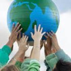 picture of a globe being held up by young people with their hands meeting together